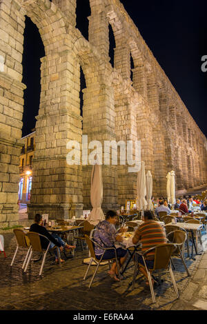 Nachtansicht des ein Außenrestaurant mit römischen Aquäduktbrücke hinter Segovia, Kastilien und Leon, Spanien Stockfoto