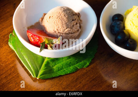 Schüssel mit Schokoladen-Sorbet oder Eis mit Erdbeere, neben einer Schale der Zitronensorbet oder Eis mit Heidelbeeren Stockfoto