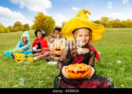 Schönes Mädchen in Hexenkostüm hält geschnitzten Kürbis Stockfoto