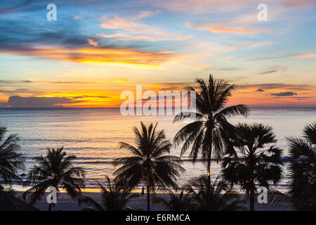 Sonnenuntergang über dem Meer, Surin Beach, Phuket, Thailand mit Silhouetten von Palmen gegen einen lebendigen bunten Himmel Stockfoto