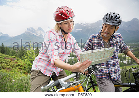 Paar auf Mountainbikes lesen Karte am Hang