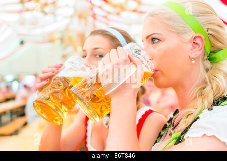 Frauen trinken bayerisches Bier im Zelt auf dem Oktoberfest oder Dult Dirndl tragen Stockfoto