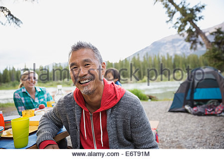 Mann lächelnd an Picknick-Tisch auf Campingplatz