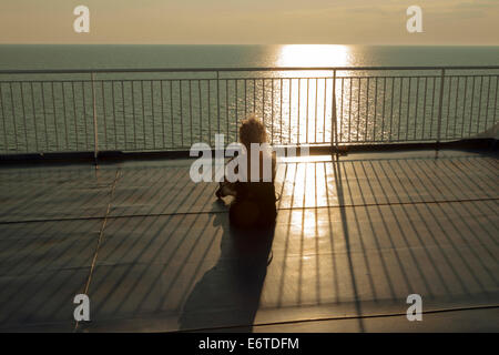 Eine Frau auf dem Sonnendeck der Stena Scandinavica, ein Passagier-Fähre - die letzten Strahlen der untergehenden Sonne genießen. Stockfoto