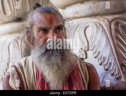 Ein Hindu Sadhu (heiliger Mann), mit traditionellen Gesichts Farbe und einem weißen Bart, in einem kleinen Tempel in Jaipur, Indien, während das Holi Festival. Stockfoto