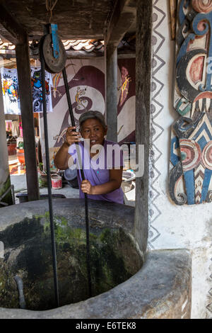 Yogyakarta, Java, Indonesien.  Frau Zeichnung Wasser aus ihrem privaten Brunnen in Nachbarschaft Family Home. Stockfoto