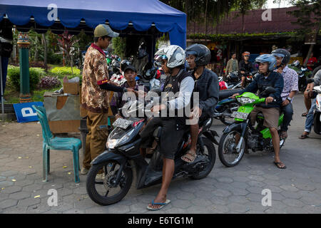 Yogyakarta, Java, Indonesien.  Bezahlen die Parkgebühr vor dem Verlassen der Motorrad-Parkplatz an der Vogelmarkt. Stockfoto