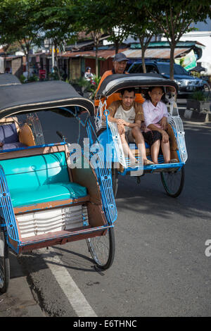 Yogyakarta, Java, Indonesien. Mann und Frau in einem Becak, ein dreirädriges Fahrzeug Powered by menschlichen Antrieb fahren.  Malioboro St. Stockfoto