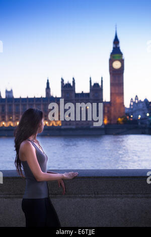 Eine junge Frau stand vor den Houses of Parliament in London in der Abenddämmerung Stockfoto
