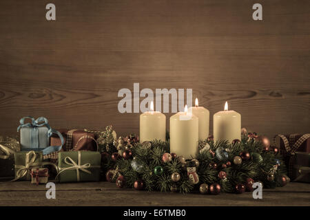 Adventskranz oder Krone mit vier brennenden Kerzen und Weihnachtsgeschenke für einen Gutschein. Stockfoto