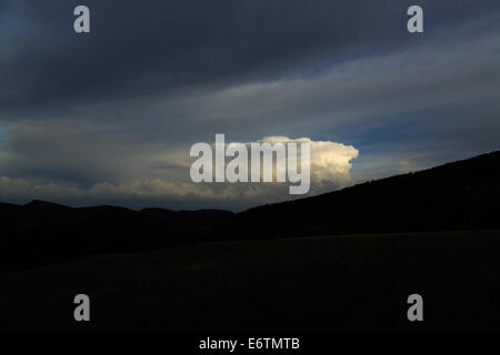 Ein Foto von einigen Cumulus Sturmwolken über einen abgedunkelten hügelige Landschaft zu bauen. Cumulonimbus ist eine Dichte hoch aufragenden vertikale Stockfoto