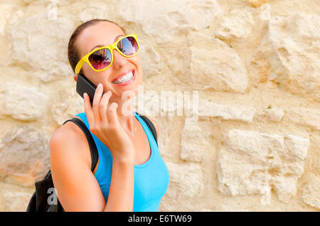 Bezaubernde Mädchen-Reisenden in gelbe Sonnenbrille spricht per Telefon Stockfoto