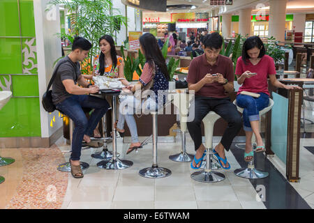 Yogyakarta, Java, Indonesien.  Ambarrukmo Shopping Mall.  Zwei junge Paare und ein Freund in der Food-Court. Stockfoto