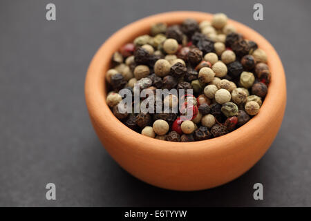 Gemischte Pfefferkörner in einer Schüssel auf schwarzem Hintergrund. Closeup. Stockfoto