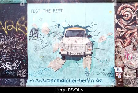 BERLIN - 24. August 2014: Die East Side Gallery ist der größte Outdoor-Kunstgalerie der Welt. Dieses Stück der Mauer zeigt ein Graffiti eines Trabant-Autos, die durch die Wand bricht Stockfoto