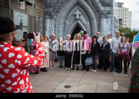 South Bank, London, UK. 30. August 2014. Hochzeitspaar und Gemeinde mit Fotografieren außerhalb einer aufblasbaren Hochzeitsschloss oder die Kirche als Teil der Süd-Banken "Festival of Love" in London England auf Samstag, 30. August 2014 Credit: Neil Setchfield/Alamy Live News Stockfoto