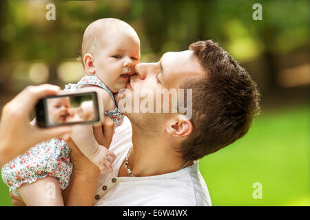 Familie mit Baby im Park nehmen Selfie per Handy Stockfoto