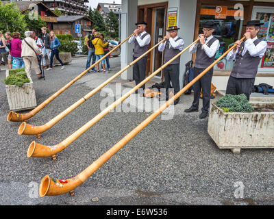 Schweizer Straßenmusikanten. Vier Alphornbläser auf einer Straße Konzert in der Schweizer Stadt Nendaz, außerhalb der Geschäfte Stockfoto
