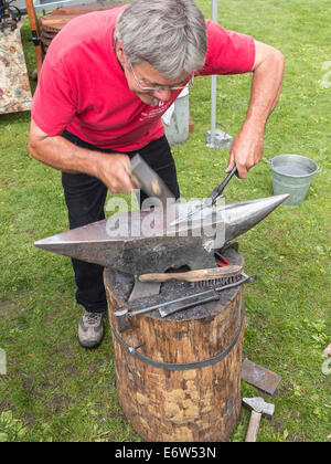 Ein Schmied Hämmern heiße Eisen in Form auf einem Amboss Stockfoto