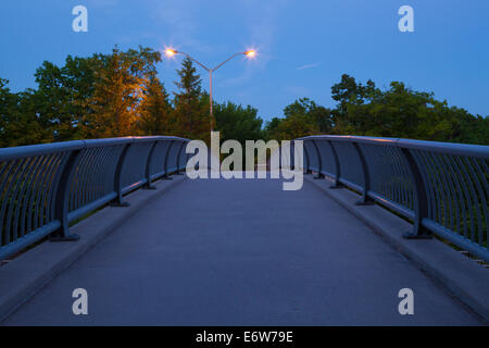 Eine Fußgängerbrücke, die Smith-Triller-Viadukt überquert, die 16 Mile Creek entlang der Dundas Street in der Abenddämmerung in Oakville, Ontario überquert Stockfoto