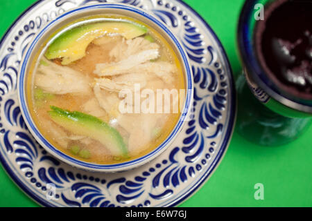 Hühnersuppe mit Avocado-Scheiben auf einem Teller Talavera in Puebla, Mexiko. Stockfoto