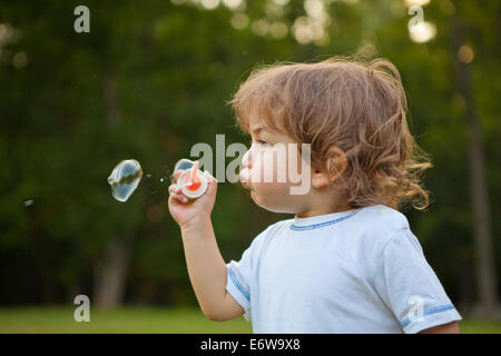 Kleiner Junge bläst Seifenblasen im Park. Stockfoto