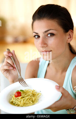 Glückliche Mädchen essen italienischen Pasta mit Tomaten, Zucchinibällchen und Basilikum. Stockfoto