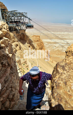 Frau geht auf Masada byzantinischen Westtor mit Seilbahn Überschrift unten auf Hintergrund, Israel. Stockfoto