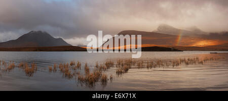 Blick vom man ein Ais bis zu den Gipfeln des Inverpolly Nature Reserve mit einem Regenbogen über dem See, Ullapool, Sutherland, Scotla Stockfoto