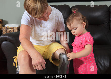 Großmutter mit Beinprothese mit ihrem Enkelkind spielen mit der Prothese Stockfoto