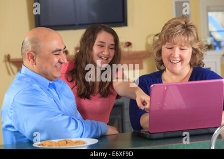 Tochter mit Vater und Mutter lachend auf laptop Stockfoto