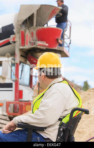 Bauleiter mit Spinal Cord Injury betrachtet man Betonmischer LKW Stockfoto