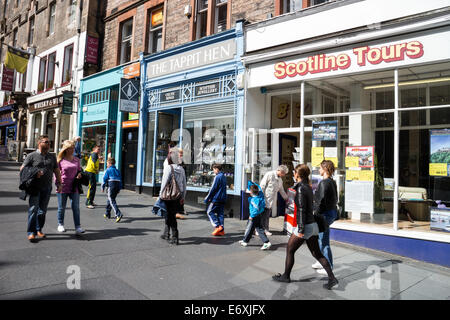 Shopping-Fans und Touristen zu Fuß vorbei an Geschäften auf der Royal Mile, Edinburgh Stockfoto