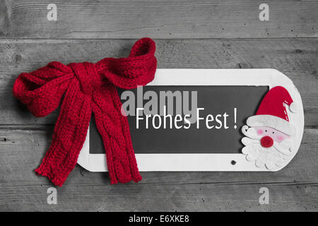 Rote Schleife auf Speisekarte an Bord mit Merry Christmas - Frohes Fest - Deutsche Botschaft auf hölzernen Hintergrund Stockfoto