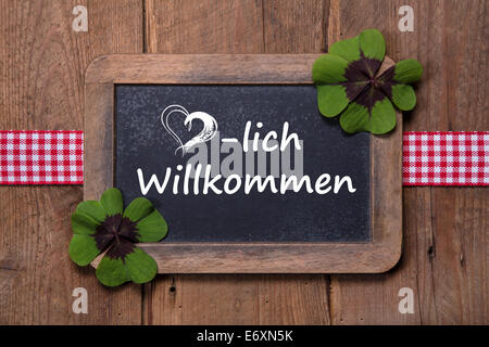 Alten Speisekarte an Bord mit Willkommensnachricht in Deutsch - Kleeblätter und Band auf hölzernen Hintergrund Stockfoto