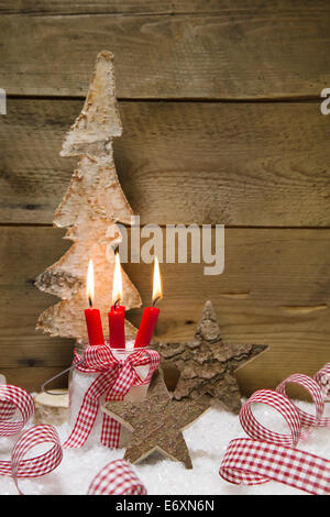 Advent: vier rote brennende Kerzen mit Weihnachten Dekoration Bändern, hölzerne Sterne und Baum auf hölzernen Hintergrund Stockfoto