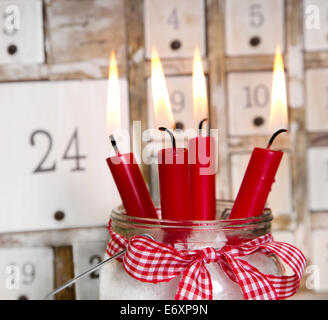 Heiligabend: vier rote brennende Kerzen mit einer schäbigen weißen Advent Kalender Hintergrund Stockfoto