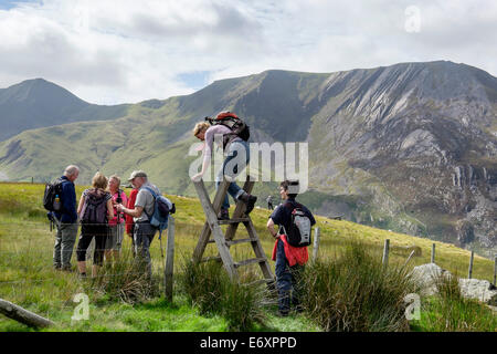 Wanderer klettern über eine Leiter Stil mit Carnedd Y Filiast und Mynydd Perfed jenseits in Snowdonia National Park (Eryri) Gwynedd North Wales UK Stockfoto