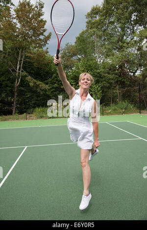 Tennisspielerin in Aktion auf einem Hof, stretching, um den Ball zu schlagen Stockfoto