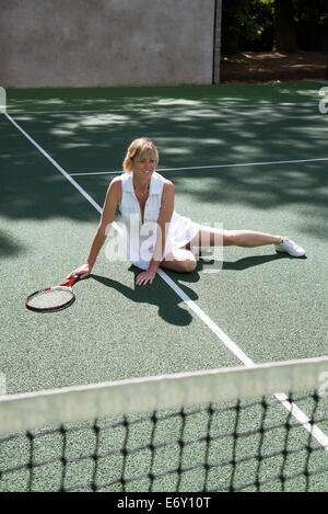 Attraktive weibliche Tennisspieler auf dem Platz gefallen ist vom Boden aufstehen. Stockfoto