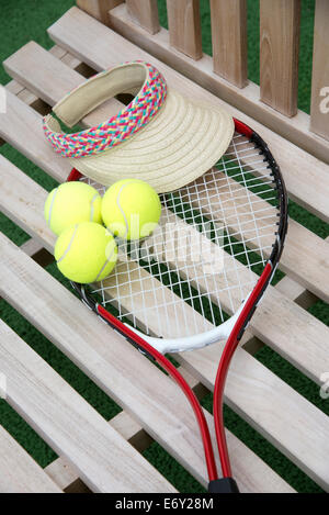 Tennis-Schläger-Kugeln und Sonnensegel auf einem hölzernen Sitz Stockfoto