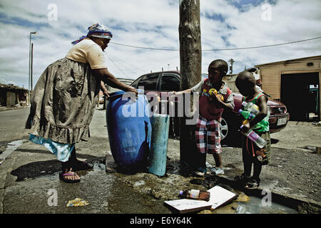 Eine Frau und zwei Kindern an die öffentliche Wasserversorgung Registerkarte Township Langa, Cape Town, Südafrika, Afrika Stockfoto