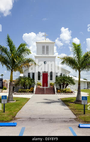 Bürgersteig, rote vordere Eingangstür und Kirchturm Gemeinschaft auf Broadway Avenue West in Everglades City, Florida, USA. Stockfoto