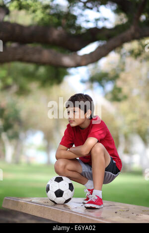 Kleiner Junge im Park auf einem Tisch mit Fußball Stockfoto