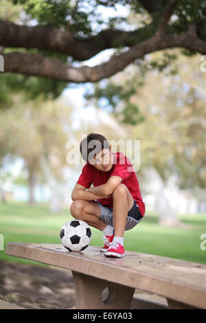 Kleiner Junge im Park auf einem Tisch mit Fußball Stockfoto