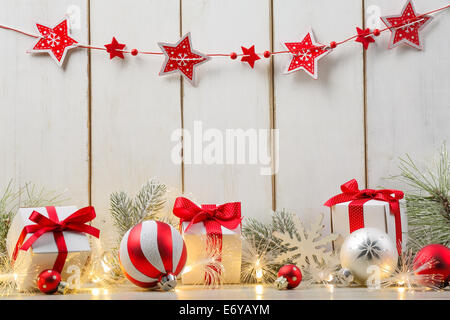 Weihnachtskugel, Geschenke, Tanne Zweig und Lichter auf Holzbrett. Stockfoto