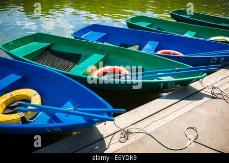 Freizeitboote am Pier in einer Reihe warten auf Urlauber, sie zu mieten. Grünes Wasser von einem Stadt-Teich Stockfoto