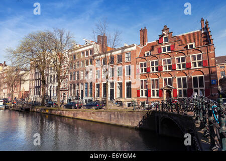 AMSTERDAM, Niederlande - 19. März 2014: Bunte Häuser entlang dem Kanal-Damm im Frühling. Normale Menschen gehen Stockfoto