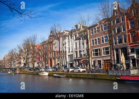 AMSTERDAM, Niederlande - 19. März 2014: Bunte Häuser am Kanal in sonnigen Frühlingstag Fassaden. Normale Menschen gehen Stockfoto