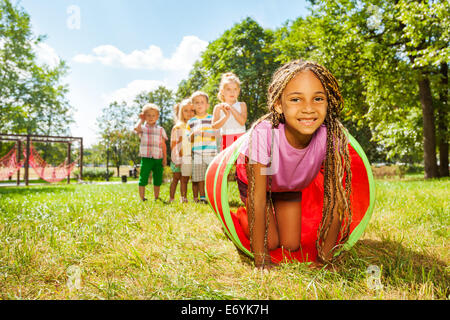 Afrikanische Mädchen zu spielen, krabbeln durch Rohr im park Stockfoto